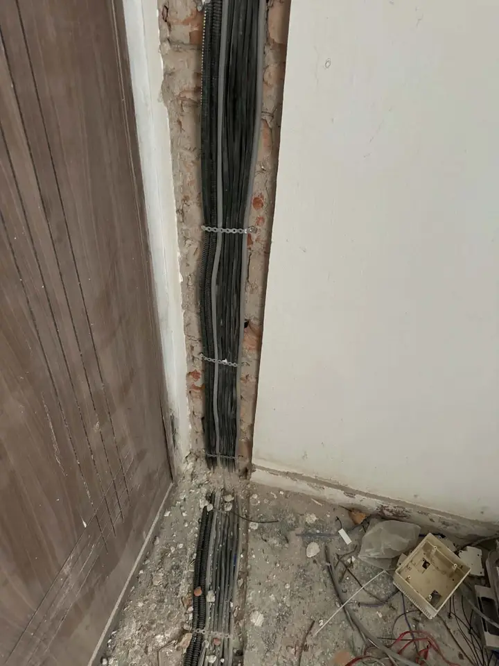 Cabluri negre într-o ștrobă lungă lângă toc, cu moloz pe pardoseală
