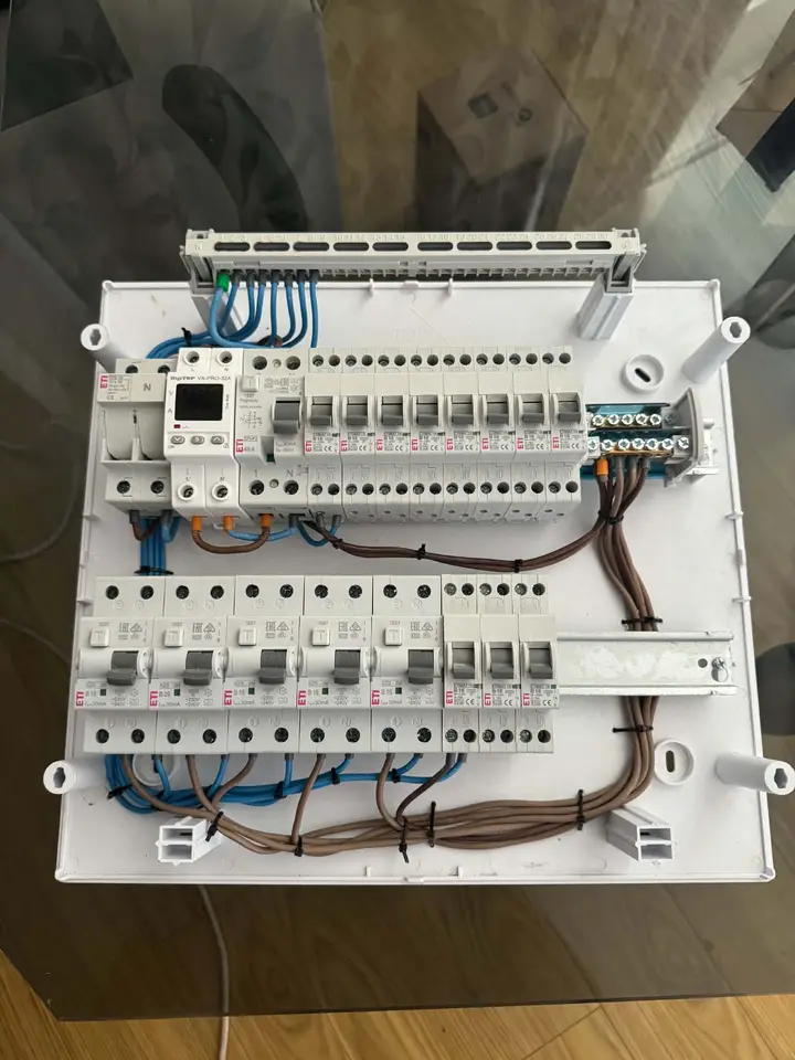 Tablou electric cablat, văzut de sus, cu aparate de protecție, fire albastre și maro și bară de nul, pus pe o masă
