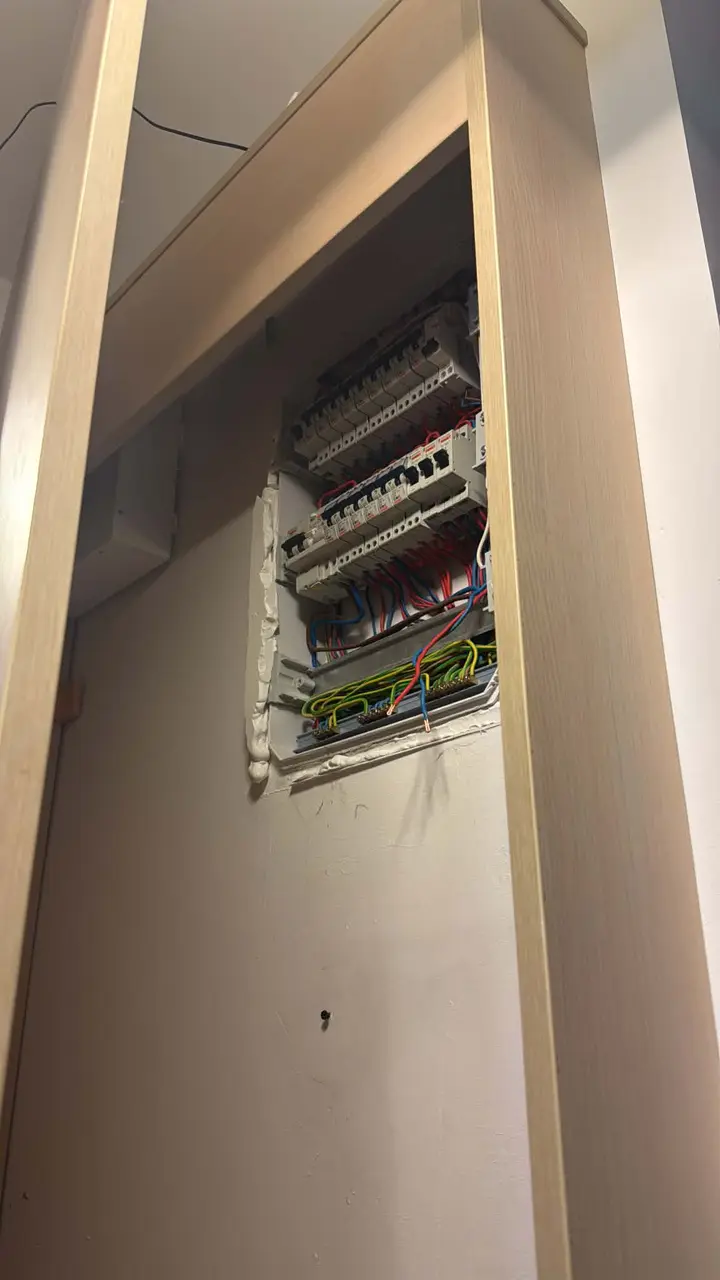 Tablou electric cablat într-o nișă din perete, văzut de jos, în spatele unui cadru de ușă
