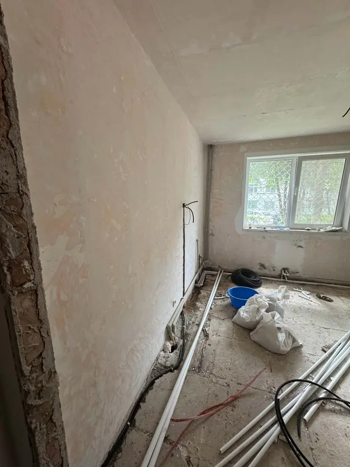 Cameră cu fereastră, cu tuburi albe și un tub negru de-a lungul peretelui, înainte de finisaje
